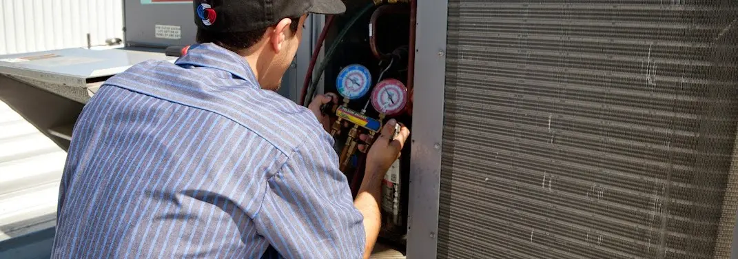 HVAC technician servicing a condenser unit in Selah